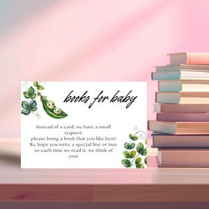 May include: A white card with the text "books for baby" and a watercolor illustration of two peas in a pod. The card requests guests to bring a book. A stack of books is visible in the background.