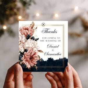 May include: Square wedding thank you card with floral design. The card features a gold border and the words "Thanks for coming to the wedding of Daniel & Samantha." The card has a watercolor floral arrangement in shades of pink, white, and navy.