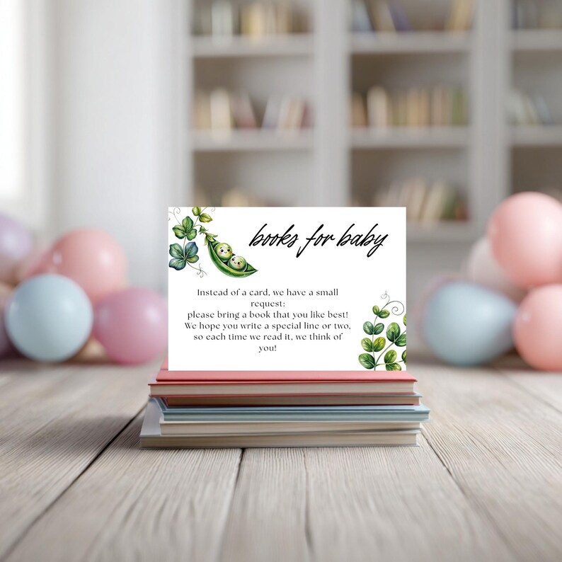 May include: A stack of books topped with a white card featuring the text "books for baby." The card has a green pea pod illustration with two baby faces inside. The card requests guests bring a book and write a special line.