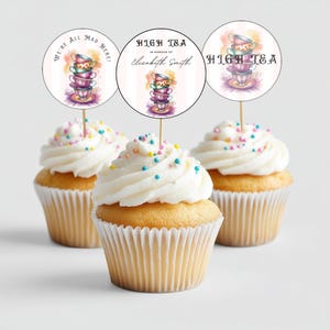 Puede incluir: Tres adornos para cupcakes con tazas de té de colores y el texto "We're All Mad Here!" y "High Tea in Honour of Elizabeth Smith" y "High Tea".