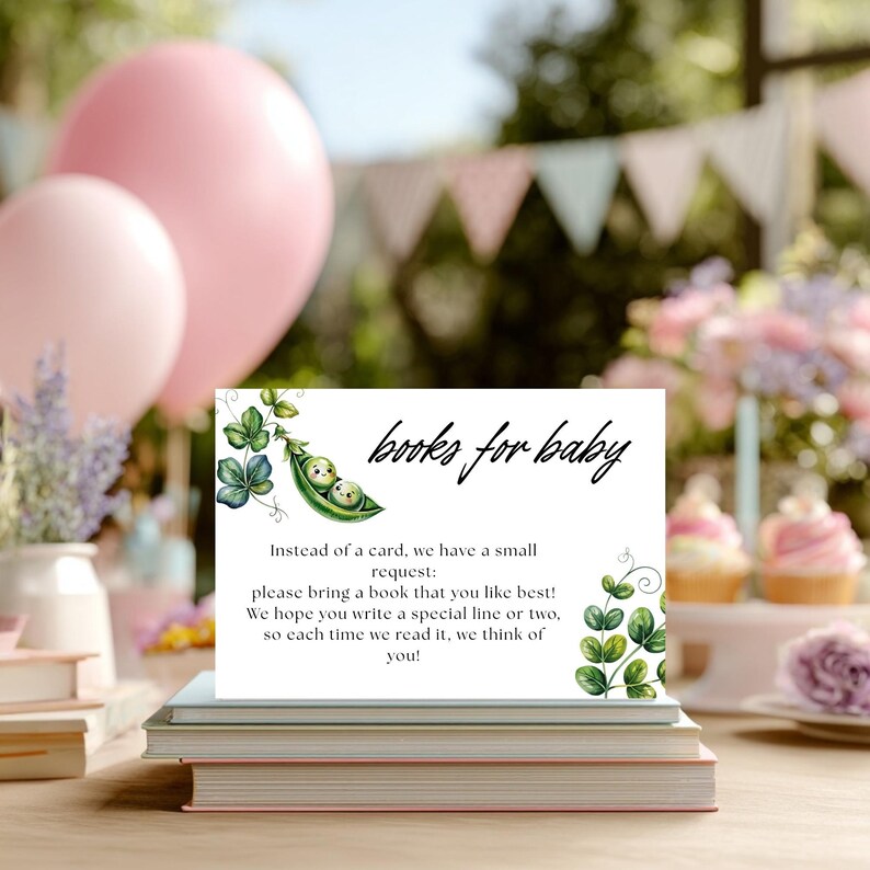 May include: A white card with the text "books for baby" and a request for guests to bring a book. The card is decorated with green pea pod and leaf illustrations. Pink balloons and books are in the background, suggesting a baby shower theme.