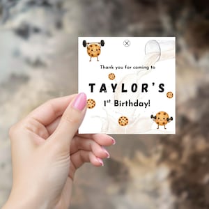 Peut inclure: Carte d'anniversaire carrée avec le texte "Thank you for coming to TAYLOR'S 1st Birthday !" entourée de biscuits de dessins animés et d'éclaboussures de lait. Deux biscuits lèvent des poids.