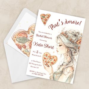 May include: A watercolour bridal shower invitation with the text "That's Amore!". The design includes a heart-shaped pizza illustration and a portrait of a woman holding a pizza. The envelope also features a heart-shaped pizza.