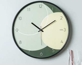 May include: A black and green round wall clock with black hands and white numbers. The clock has a geometric design with overlapping circles.