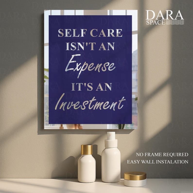 May include: A framed wall art print with the text "SELF CARE ISN'T AN Expense IT'S AN Investment" in silver lettering on a dark blue background. The image also shows white cosmetic bottles with gold lids.