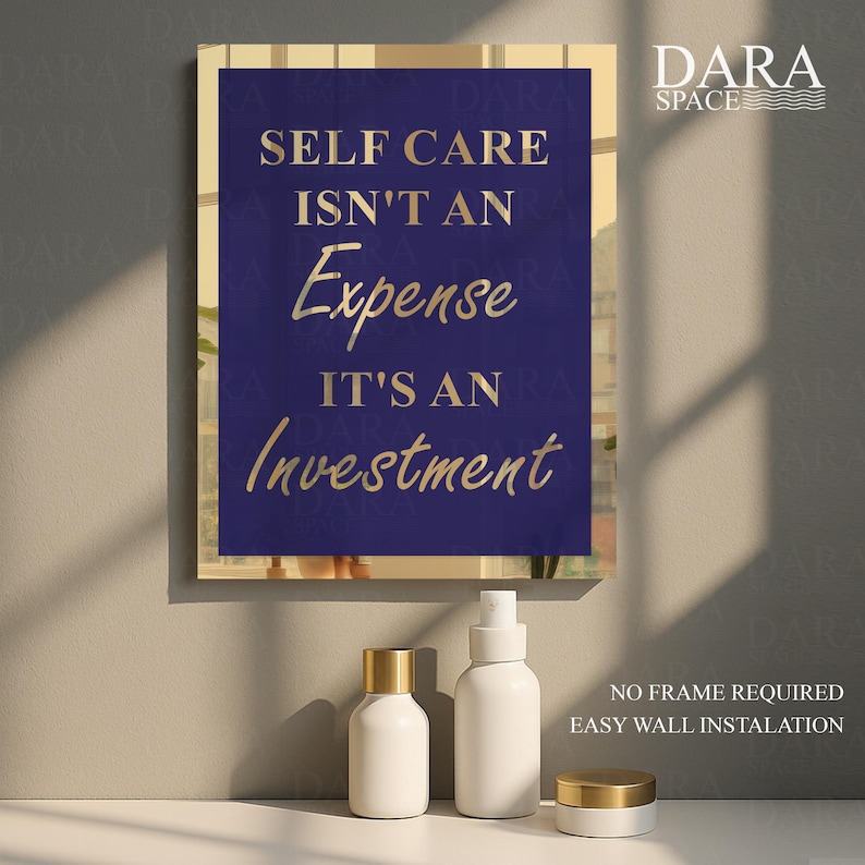 May include: A framed wall art print with the text "SELF CARE ISN'T AN Expense IT'S AN Investment" in gold lettering on a navy blue background. The print is displayed with white cosmetic bottles with gold lids.