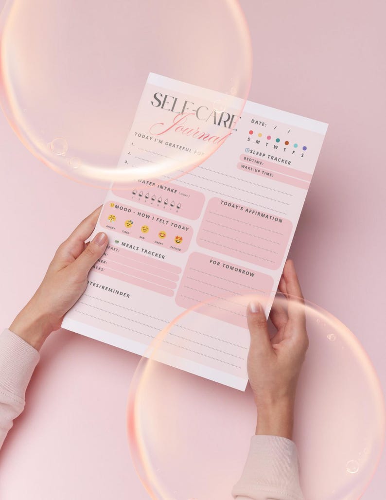 Pu&ograve; includere: Un diario di cura di s&eacute; rosa e bianco con le parole "SELF-CARE Journal" in elegante scrittura. Il diario include sezioni per la gratitudine, l'assunzione di acqua, il monitoraggio dell'umore, i pasti e le affermazioni. Il diario &egrave; tenuto da una persona.
