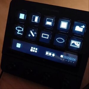 May include: A black MARS GAMING control panel with multiple illuminated square buttons displaying various white icons. The panel has a lower section with a series of white icons and numbers. The buttons and icons glow with a blue light.
