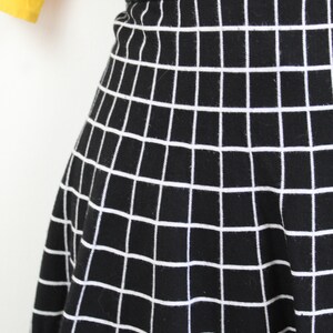 May include: Black skirt with a white grid pattern. The skirt is a-line and has a high waist.