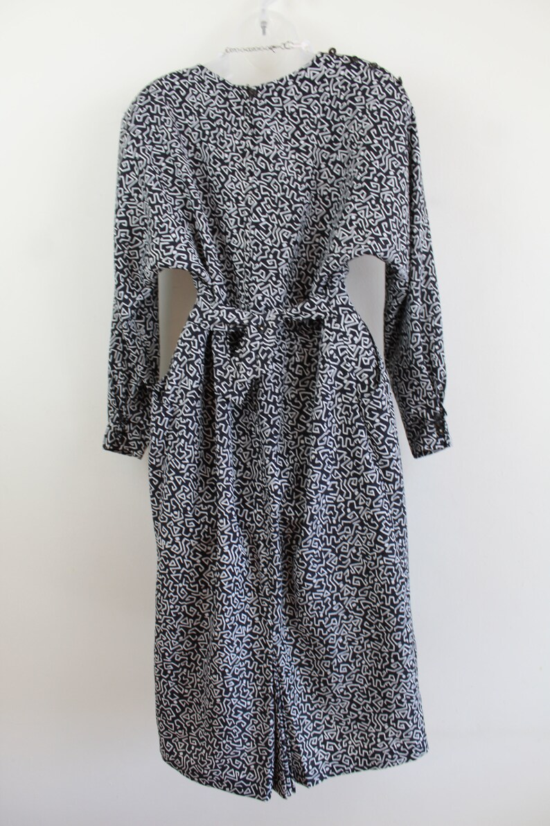 Puede incluir: Un vestido de manga larga con estampado en blanco y negro con un lazo en la cintura.