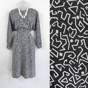 Puede incluir: Un vestido midi de estampado geom&eacute;trico en blanco y negro con mangas largas y cintura ajustada. El vestido tiene un dise&ntilde;o simple y elegante y es perfecto para una variedad de ocasiones.