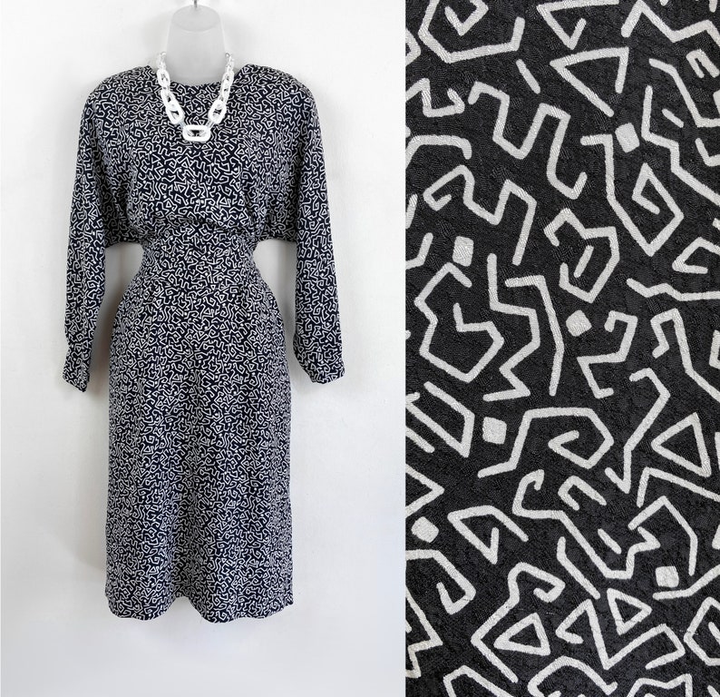 Puede incluir: Un vestido midi de estampado geom&eacute;trico en blanco y negro con mangas largas y cintura ajustada. El vestido tiene un dise&ntilde;o simple y elegante y es perfecto para una variedad de ocasiones.