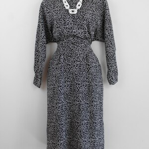 Puede incluir: Un vestido negro y blanco con estampado de l&iacute;neas blancas sobre fondo negro. El vestido tiene mangas largas y una cintura ajustada.