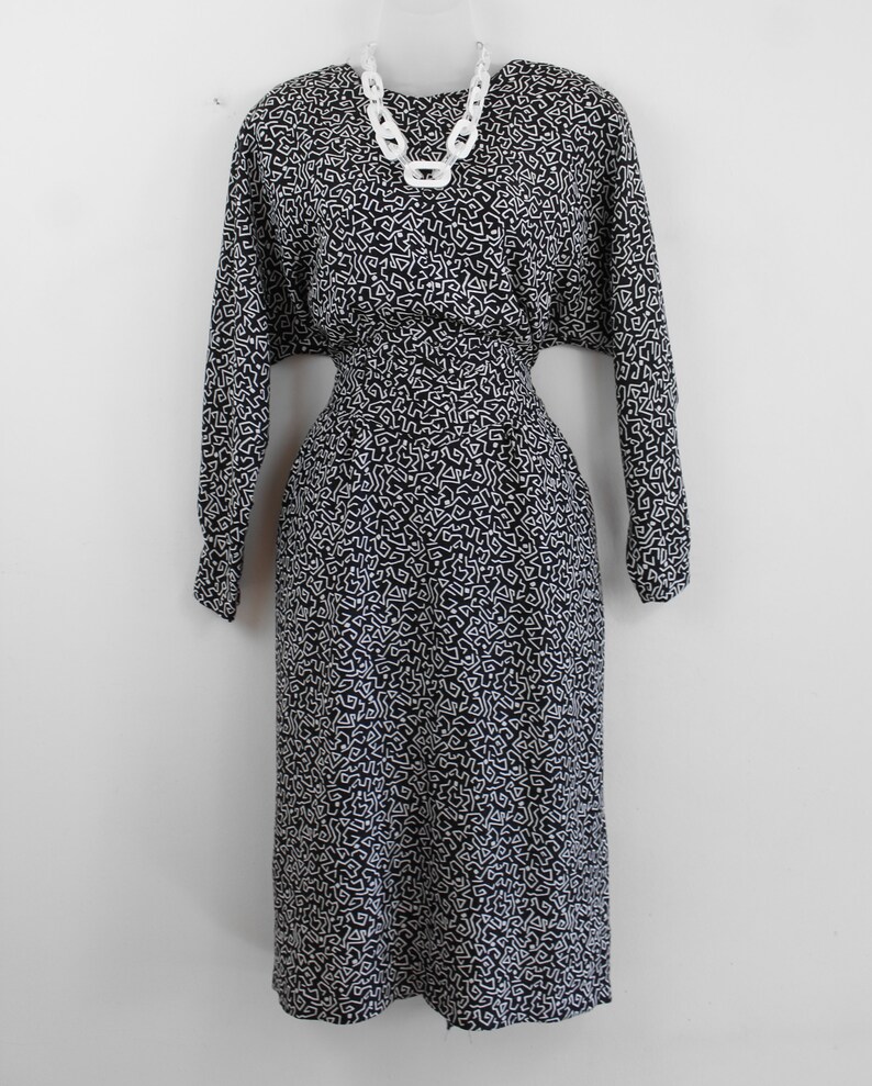 Puede incluir: Un vestido negro y blanco con estampado de l&iacute;neas blancas sobre fondo negro. El vestido tiene mangas largas y una cintura ajustada.