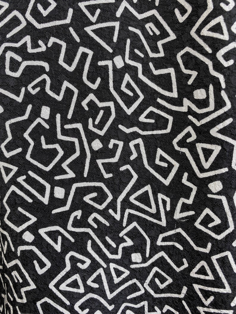 Puede incluir: Tela negra con un patr&oacute;n geom&eacute;trico blanco. El patr&oacute;n est&aacute; formado por l&iacute;neas y formas que crean un dise&ntilde;o complejo.