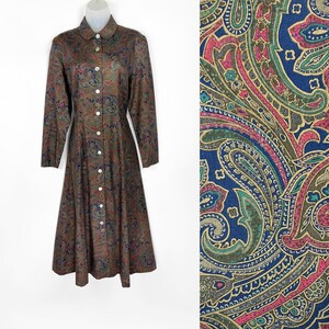 May include: A long-sleeved button-down dress with a paisley print in shades of brown, blue, red, and gold. The dress has a collared neckline and a flared skirt.