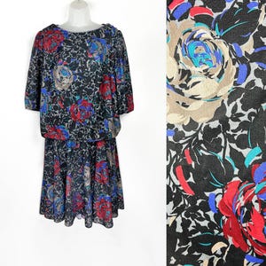 May include: A black and gray floral print dress with a short sleeve top and a skirt. The dress has a gathered waist and a loose fit.