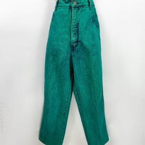 May include: Bright green acid wash jeans with a high waist. The jeans have a classic five-pocket design and a button and zipper closure. The pants are shown with a black and white striped top.