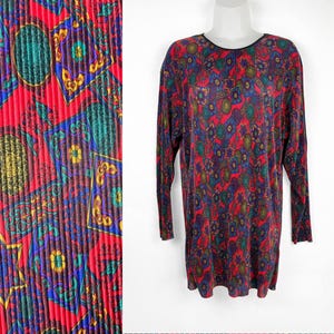 May include: A red, blue, and green long-sleeved shirt with a geometric pattern. The shirt is made of a pleated fabric.