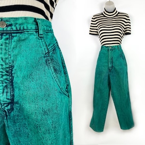 May include: Bright teal acid wash jeans with a high waist and a button closure. The jeans are paired with a black and white striped top. The jeans have a classic five-pocket design and a straight leg.