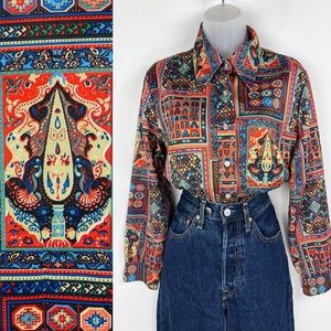 May include: A long-sleeved button-down shirt with a colorful geometric pattern. The shirt is made of a silky fabric and has a relaxed fit.