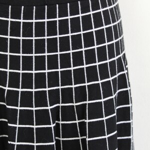 May include: Black skirt with a white grid pattern. The skirt is made of a stretchy fabric and has a fitted waistband.