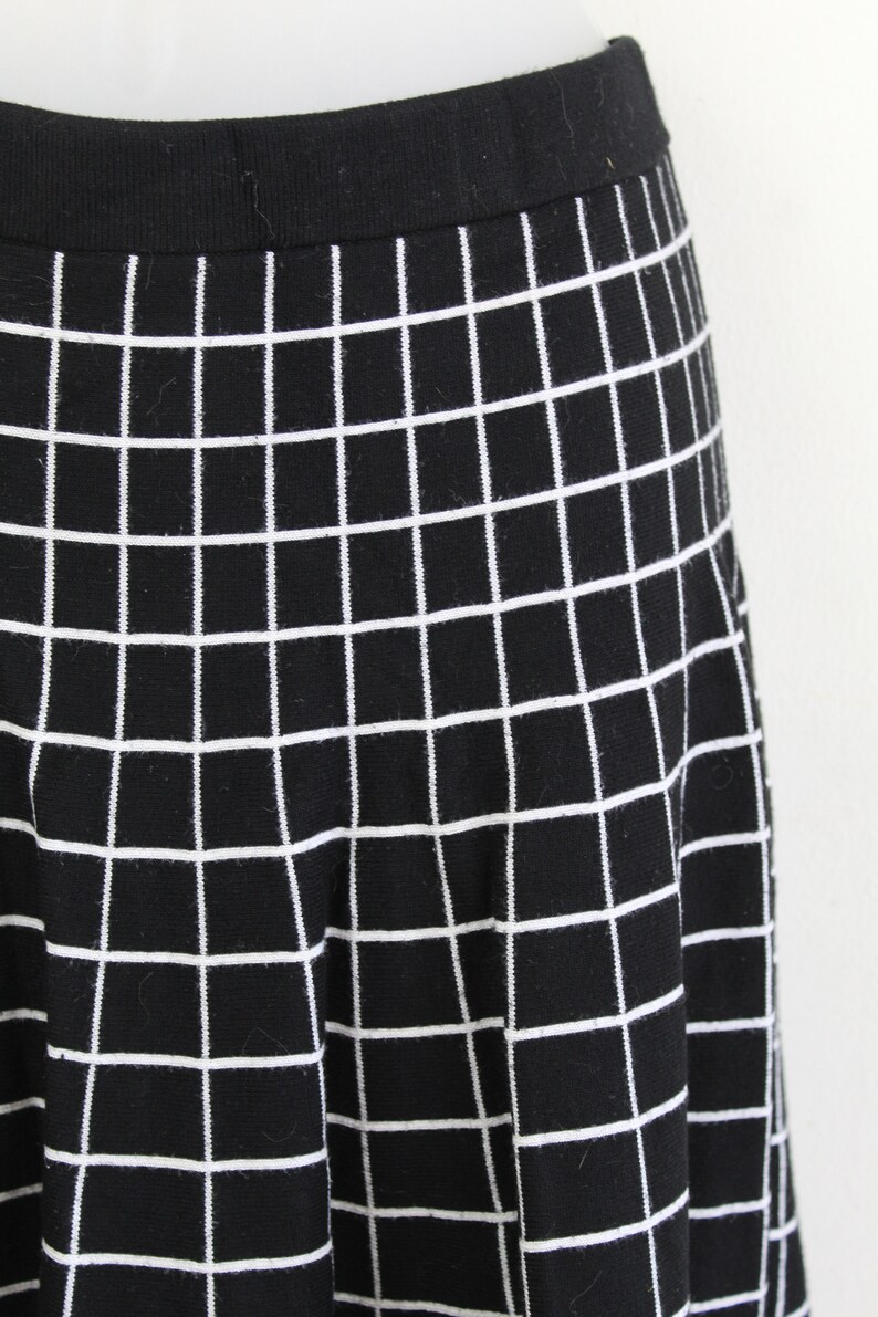 May include: Black skirt with a white grid pattern. The skirt is made of a stretchy fabric and has a fitted waistband.