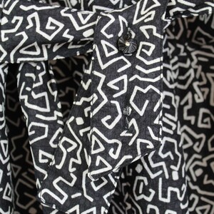 Puede incluir: Primer plano de una tela con estampado blanco y negro con un bot&oacute;n blanco. La tela tiene un dise&ntilde;o geom&eacute;trico con una superficie texturizada.