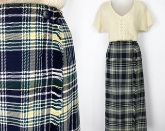 May include: A long, navy blue, green, and yellow plaid wrap skirt with a fringe detail. The skirt has a single button closure and is made of a woven fabric.