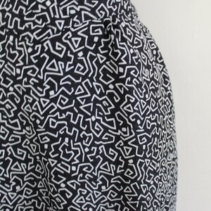 Puede incluir: Tela negra y blanca con un patr&oacute;n geom&eacute;trico. El patr&oacute;n est&aacute; formado por peque&ntilde;as l&iacute;neas blancas que crean un dise&ntilde;o laber&iacute;ntico.