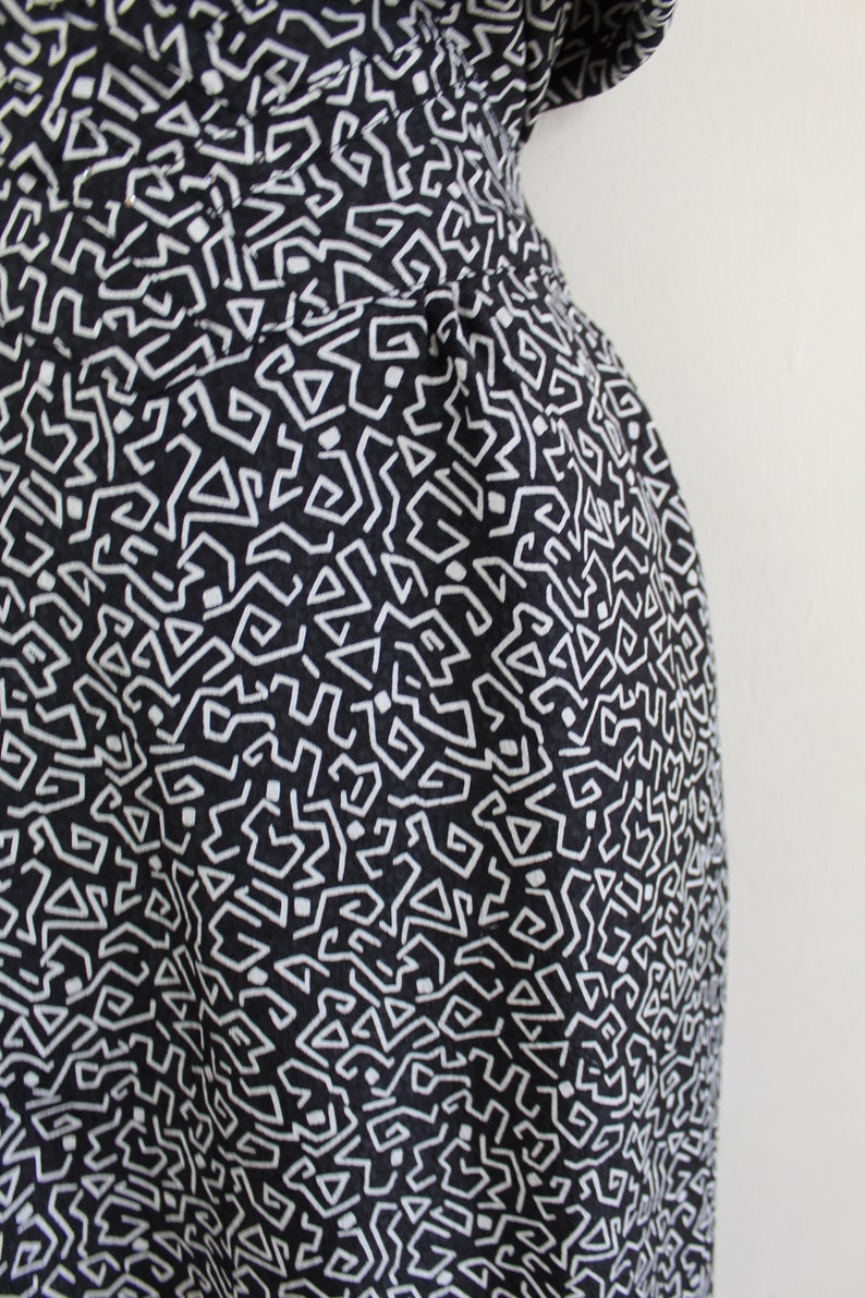 Puede incluir: Tela negra y blanca con un patr&oacute;n geom&eacute;trico. El patr&oacute;n est&aacute; formado por peque&ntilde;as l&iacute;neas blancas que crean un dise&ntilde;o laber&iacute;ntico.