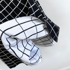 May include: Black and white checkered fabric with a white grid pattern on one side and a black grid pattern on the other side.