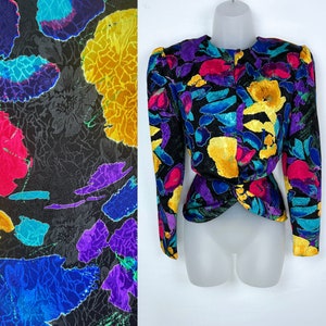 May include: A black long-sleeved jacket with a colorful abstract floral print. The print features shades of yellow, pink, purple, blue, and green.