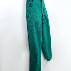 May include: Bright green acid wash jeans with a high waist and straight leg. The jeans are paired with a black and white striped top. The pants have classic five-pocket styling and a button and zipper closure.
