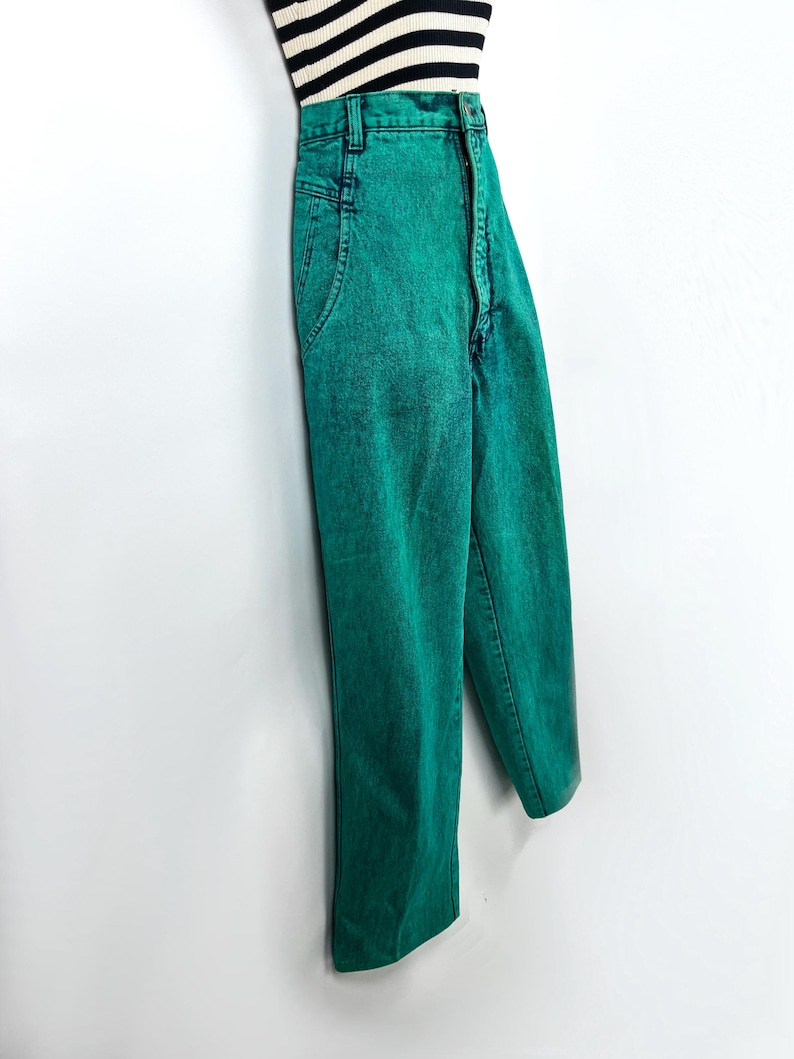 May include: Bright green acid wash jeans with a high waist and straight leg. The jeans are paired with a black and white striped top. The pants have classic five-pocket styling and a button and zipper closure.
