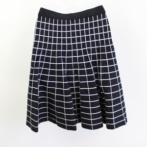 May include: A black skirt with a white grid pattern. The skirt is knee-length and has a flared silhouette.