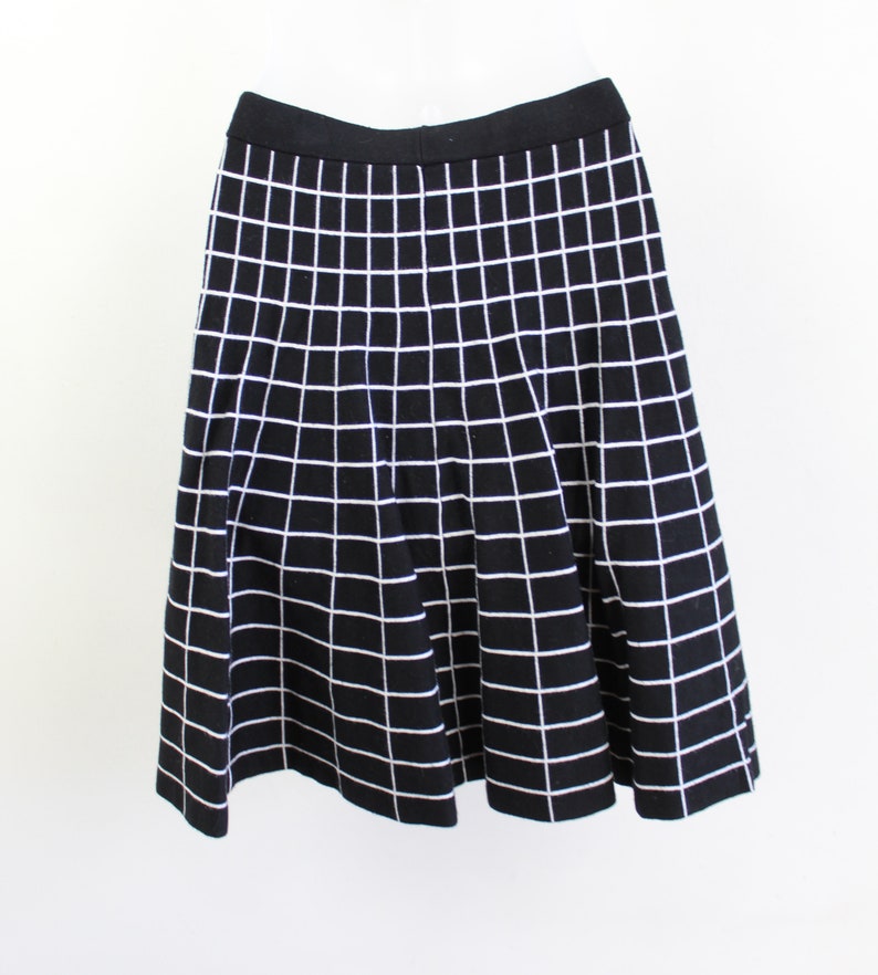 May include: A black skirt with a white grid pattern. The skirt is knee-length and has a flared silhouette.
