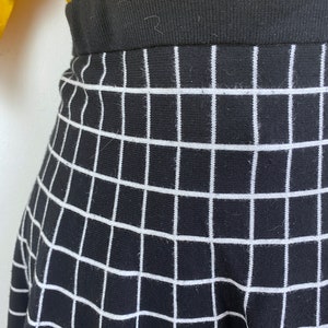 May include: Black and white checkered skirt with a black waistband. The skirt is made of a knit fabric.