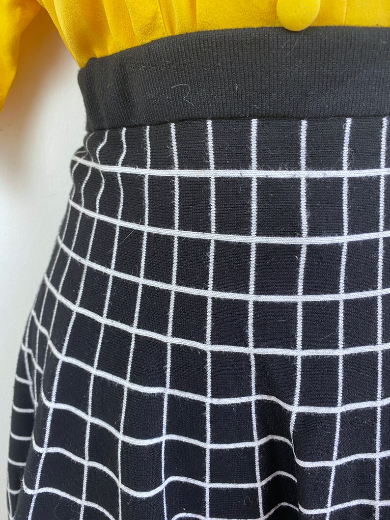 May include: Black and white checkered skirt with a black waistband. The skirt is made of a knit fabric.