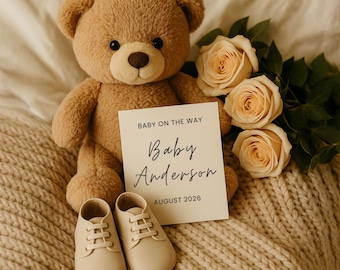 May include: A tan teddy bear, baby shoes, and peach roses are arranged on a cream-colored blanket. A card reads "Baby on the Way" with the name "Baby Anderson" and the date "August 2026". The scene suggests a baby announcement or nursery theme.