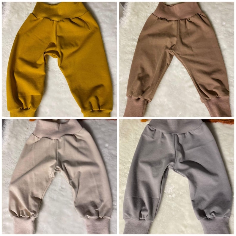 Puede incluir: Cuatro pares de pantalones de beb&eacute; en varios colores lisos: amarillo mostaza, marr&oacute;n, beige y gris. Cada par tiene una cintura alta y pu&ntilde;os en los tobillos. Los pantalones est&aacute;n hechos de una tela suave y c&oacute;moda.