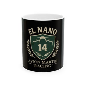 Puede incluir: Taza de cerámica negra con borde blanco. La taza presenta un logotipo verde y blanco con el texto "EL NANO", un coche estilizado, el número "14" y el texto "ASTON MARTIN RACING".