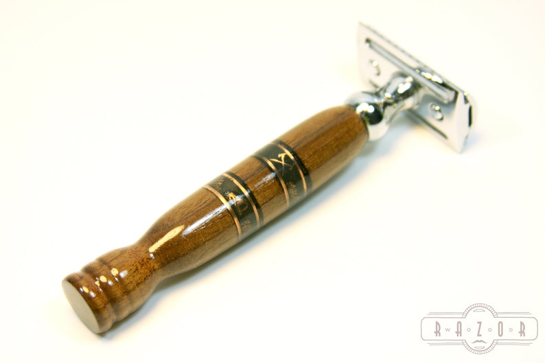 Puede incluir: Una navaja de afeitar de seguridad con mango de madera. El mango es marr&oacute;n con detalles dorados y negros. El mango tiene un dise&ntilde;o decorativo.