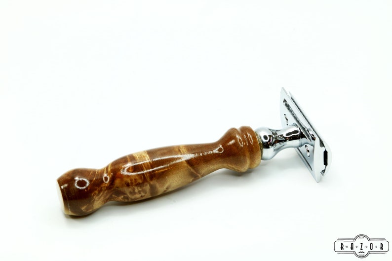 K&ouml;nnte beinhalten: Ein verchromter Sicherheitsrasierer mit einem Holzgriff. Der Griff ist aus braunem Holz mit einem Wirbelmuster.