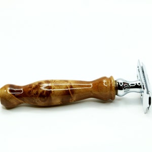 K&ouml;nnte beinhalten: Ein Sicherheitsrasierer mit einem verchromten Kopf und einem Holzgriff. Der Griff ist hellbraun mit einem marmorierten Muster.