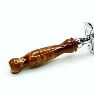 K&ouml;nnte beinhalten: Ein brauner Holz-Sicherheitsrasierer mit einem verchromten Kopf und einer polierten Oberfl&auml;che. Der Griff ist aus Holz mit einer einzigartigen Maserung.