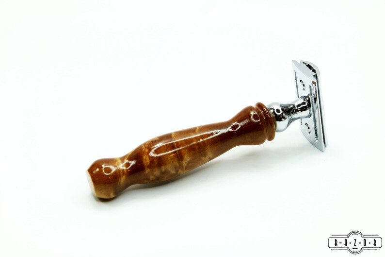 K&ouml;nnte beinhalten: Ein brauner Holz-Sicherheitsrasierer mit einem verchromten Kopf und einer polierten Oberfl&auml;che. Der Griff ist aus Holz mit einer einzigartigen Maserung.