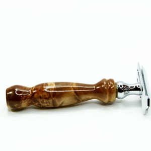 K&ouml;nnte beinhalten: Ein Sicherheitsrasierer mit einem verchromten Kopf und einem braunen Holzgriff. Der Griff hat ein marmoriertes Muster.