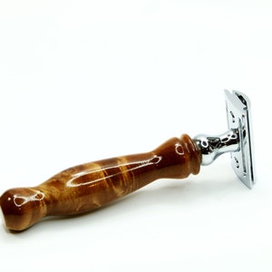 K&ouml;nnte beinhalten: Ein Sicherheitsrasierer mit einem braunen Holzgriff und einem verchromten Kopf. Der Griff hat ein Wirbelmuster.