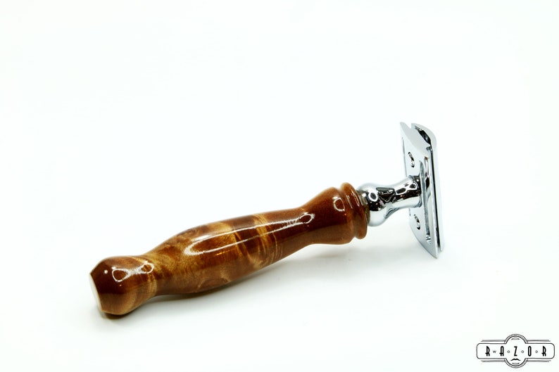 K&ouml;nnte beinhalten: Ein Sicherheitsrasierer mit einem braunen Holzgriff und einem verchromten Kopf. Der Griff hat ein Wirbelmuster.